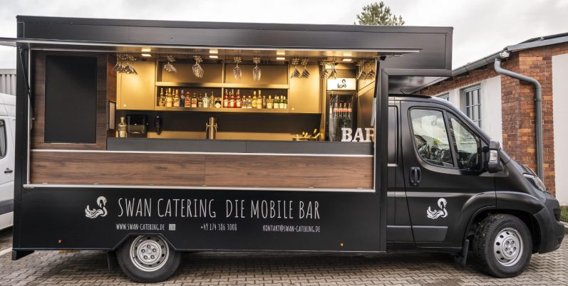 Schwarzer Getränketruck mit Holzverkleidung und offenem Fenster.