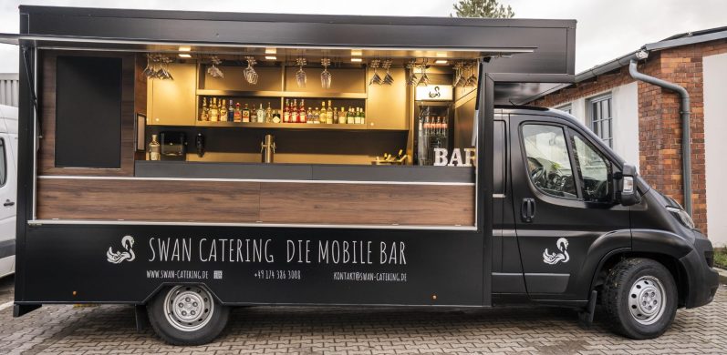 Schwarzer Getränketruck mit Holzverkleidung und offenem Fenster.