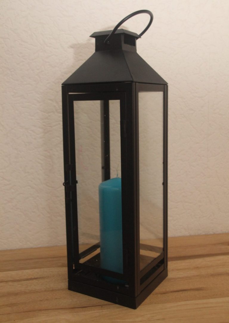 Schwarze Laterne mit Glaswänden für gemütliche Beleuchtung durch Kerzen.